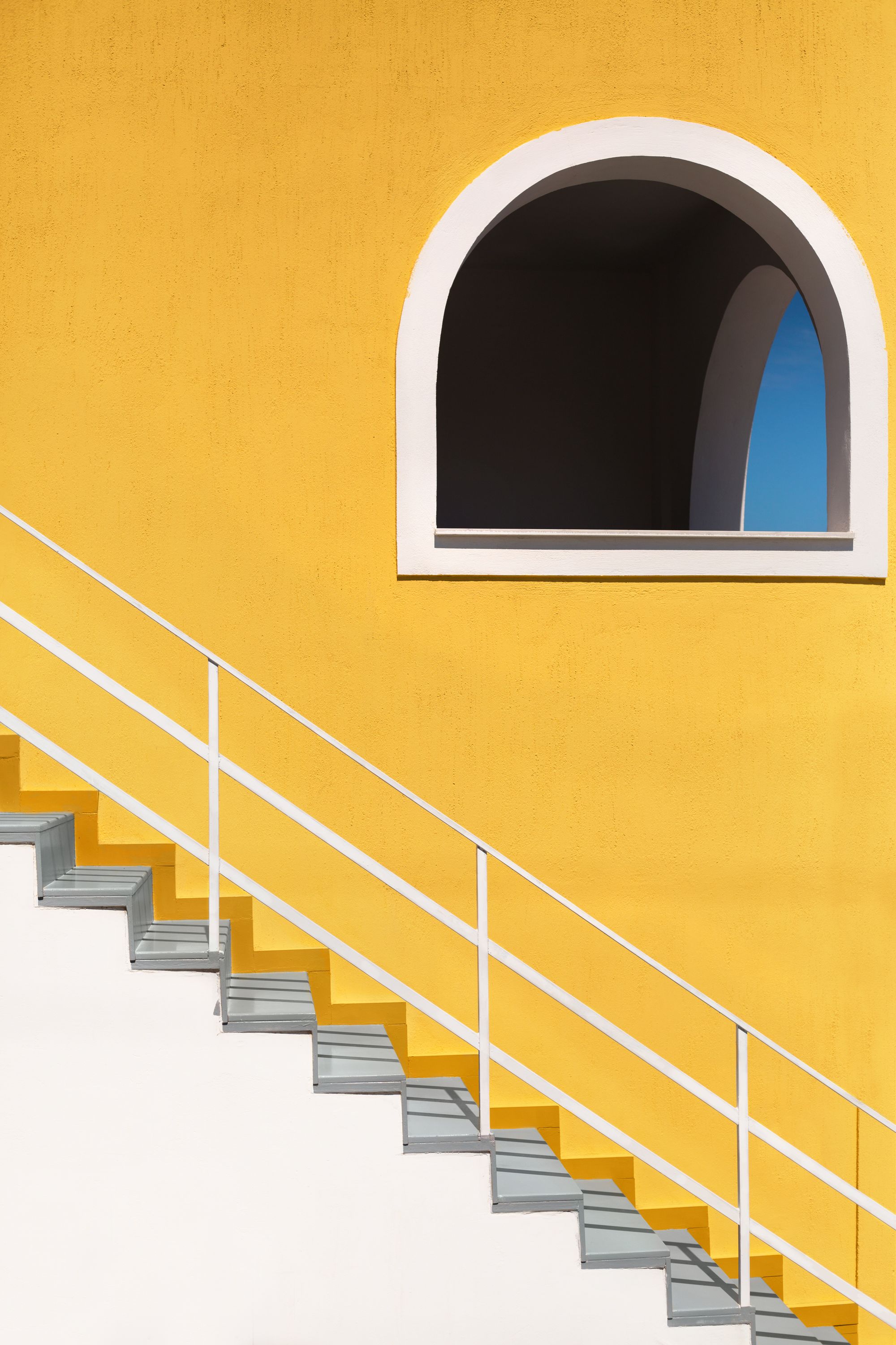 Escalera blanca sobre muro amarillo